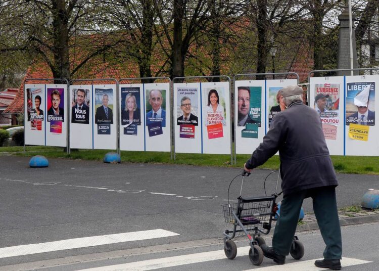 A man walks past presidential campaign posters in Estaires, northern France, on April 8, 2022. France's first round of the presidential election takes place on April 10, with a presidential runoff on April 24 if no candidate wins outright.