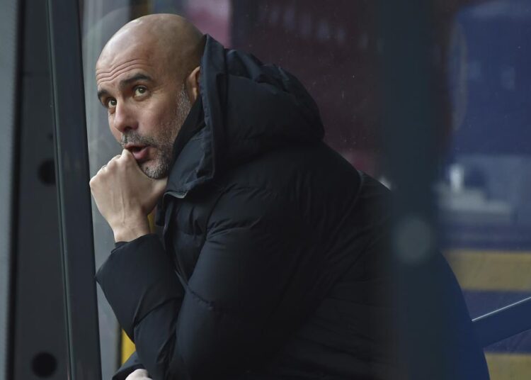 Manchester City's head coach Pep Guardiola sits on the bench before the Premier League soccer match between Burnley and Manchester City at Turf Moor, in Burnley, England, Saturday, April 2, 2022.