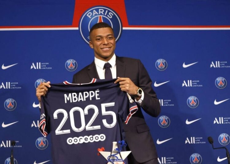 Paris St Germain's Kylian Mbappe poses holding a shirt during a press conference in Paris.