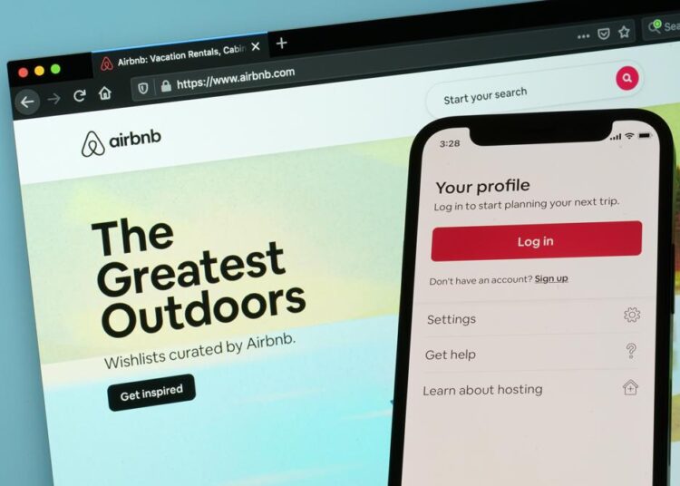 The login page for Airbnb's iPhone app is seen in front of a computer displaying Airbnb's website on May 8, 2021, in Washington.