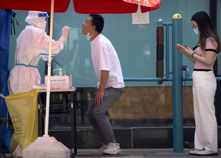A worker wearing a protective suit swabs a man's throat for a COVID-19 test at a testing site during the second consecutive day of mass testing in Beijing.
