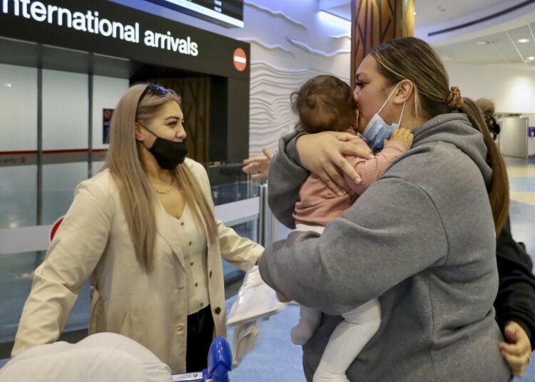 Families embrace after a flight from Los Angeles arrived at Auckland International Airport as New Zealand's border opened for visa-waiver countries Monday, May 2, 2022.