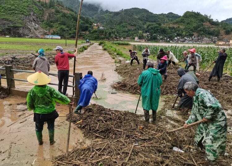 15 dead, 3 missing after torrential rains in southern China 1 - Egyptian Gazette In this photo released by China's Xinhua News Agency, people work in a flooded area in Qiubei County in southwestern China's Yunnan Province on May 27, 2022.