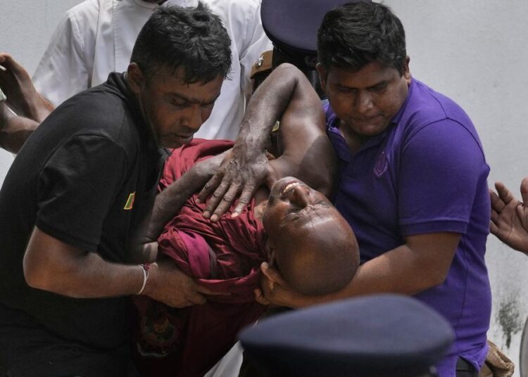 An injured Sri Lankan Buddhist monk is being carried away who among many other anti-government protesters were injured after attacked by government supporters outside prime minister Mahinda Rajapaksa's residence in Colombo, Sri Lanka, Monday, May 9, 2022. Government supporters on Monday attacked protesters who have been camped outside the offices of Sri Lanka's president and prime minster, as trade unions began a “Week of Protests” demanding the government change and its president to step down over the country’s worst economic crisis in memory.