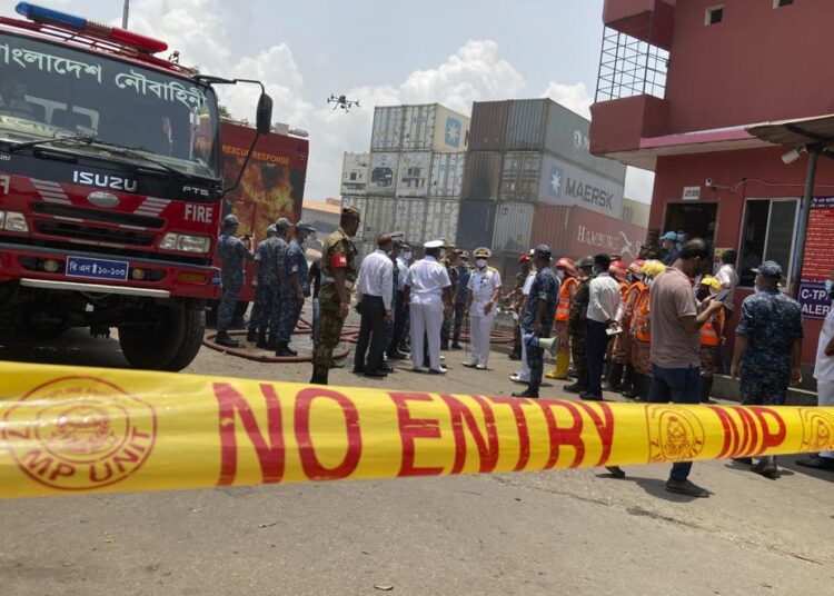 Military personnel and officials stand at the BM Inland Container Depot, where a fire broke out around midnight Saturday in Chittagong, about 210 kilometers (130 miles) southeast of, Dhaka, Bangladesh, Monday, June 6, 2022. Dozens of people were killed and more than 100 others were injured after the inferno broke out following explosions in a container full of chemicals.