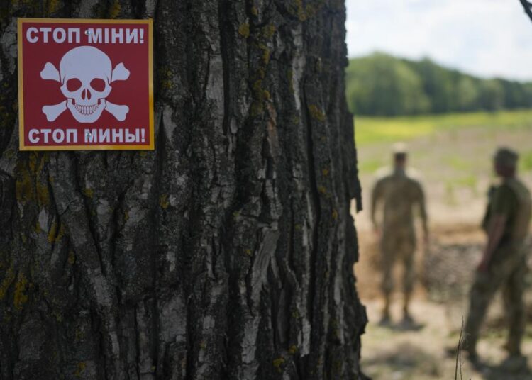 A notice warning about land mines is attached to a tree as a Ukrainian specialised team searches for mines in a field in the outskirts of Kyiv, Ukraine, Thursday.