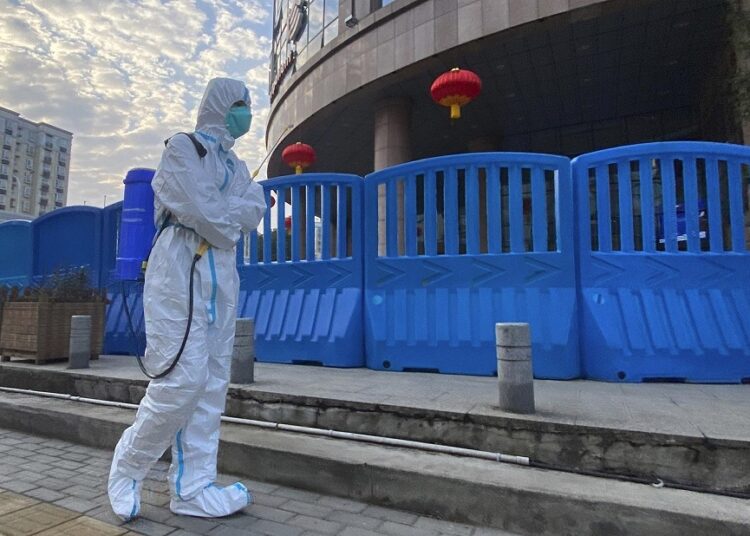 A file photo shows a worker in protectively overalls and carrying disinfecting equipment walks outside the Wuhan Central Hospital, China on Feb. 6, 2021.