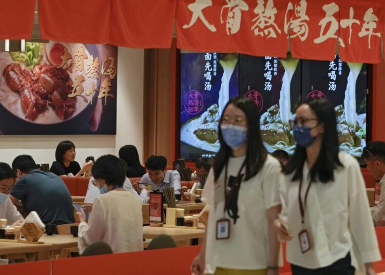 Women wearing face masks walk by a reopened restaurant in a shopping mall as new COVID-19 cases drop in Beijing Monday, June 6, 2022.