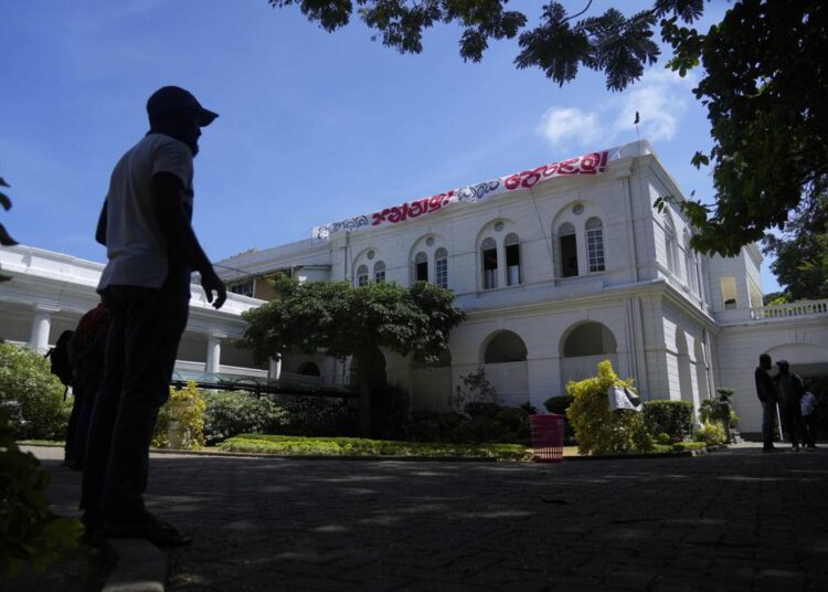 A protester standing outside the official residence of President Gotabaya Rajapaksa in in Colombo, Sri Lanka, Thursday. With the country sinking into political chaos, Rajapaksa and his wife fled to the Maldives on Wednesday aboard an air force jet. He made the prime minister acting president in his absence — a move that further roiled passions among a public that blames Rajapaksa for an economic crisis that has caused severe shortages of food and fuel.