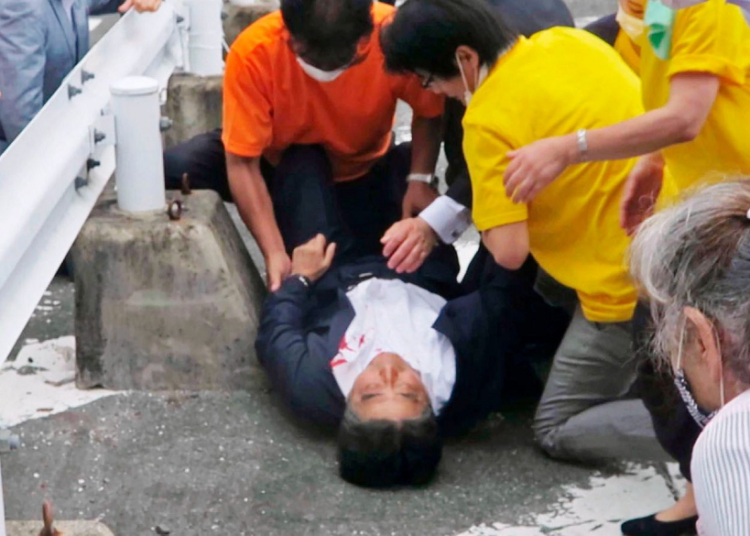 In this image from a video, Japan's former Prime Minister Shinzo Abe, center, is attended on the ground in Nara, western Japan Friday, July 8, 2022. Abe was shot and critically wounded during a campaign speech Friday. He was airlifted to a hospital but officials said he was not breathing and his heart had stopped.