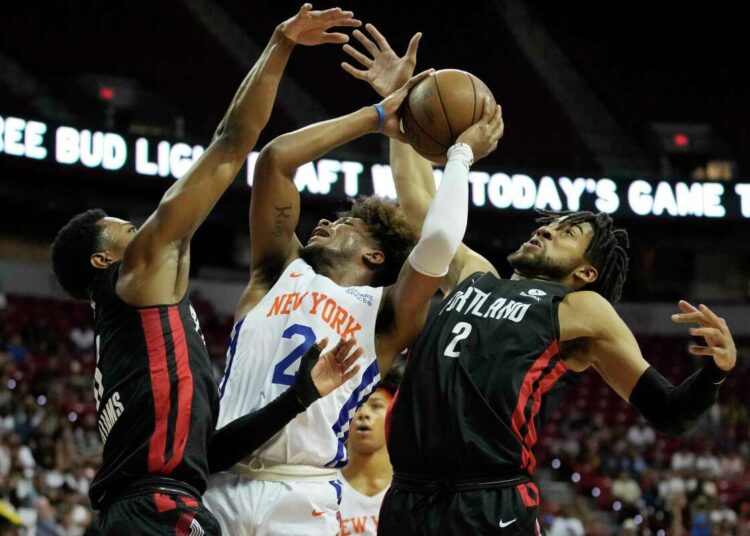 New York Knicks' Miles McBride (C) attempts a shot against Portland Trail Blazers' Brandon Williams (L) and Trendon Watford (R) during the NBA summer league championship.