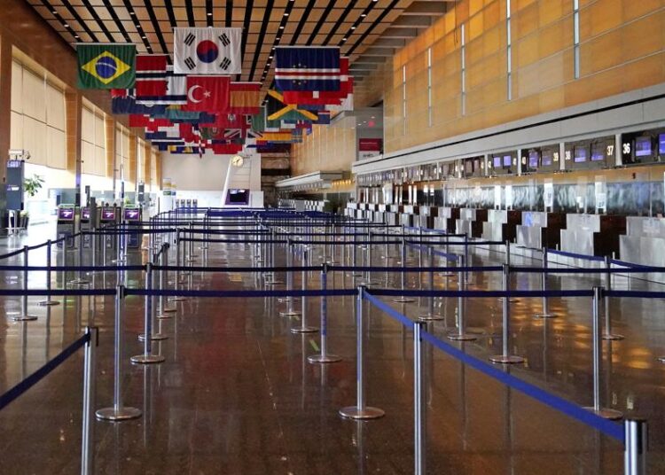 FILE - Flags of countries of the world hang over an empty Terminal E, at Logan Airport in Boston, Sept. 29, 2020. The Biden administration says it will spend nearly $1 billion to upgrade airports around the country. The Federal Aviation Administration said Thursday that the money will go to 85 different airports.