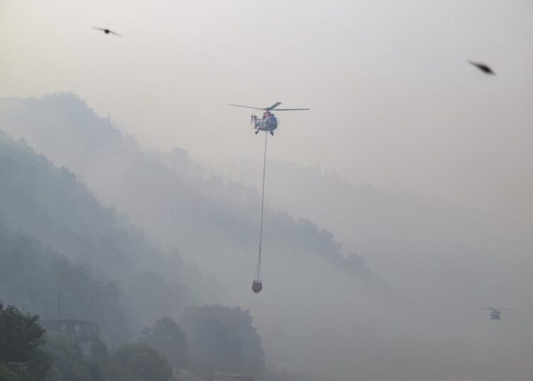 A cargo helicopter from Austria takes water from the Elbe River with an external water tank to extinguish a fire in the Saxon Switzerland National Park, Schmilka, Germany. The forest fire in the Saxon Switzerland National Park is spreading.