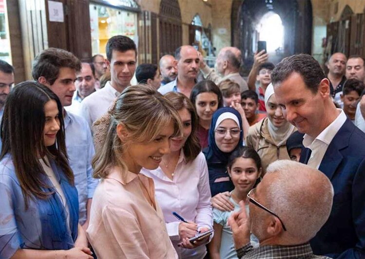 Syria s President Bashar al-Assad (R) and Asma al-Assad (C) greeting people at Aleppo s historic souk.