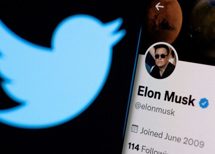 Elon Musk's twitter account is seen on a smartphone in front of the Twitter logo in this photo illustration taken, April 15, 2022.
