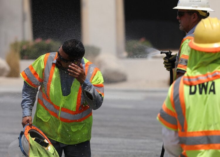 A Desert Water Agency worker is sprayed to cool him down in Palm Springs, California.