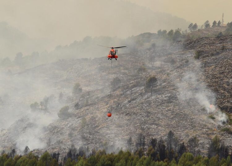 Spain: 10 injured while leaving stopped train near wildfire 1 - Egyptian Gazette A firefighter helicopter works above a wildfire advances in Viver, eastern Spain, on Wednesday, August 17, 2022.