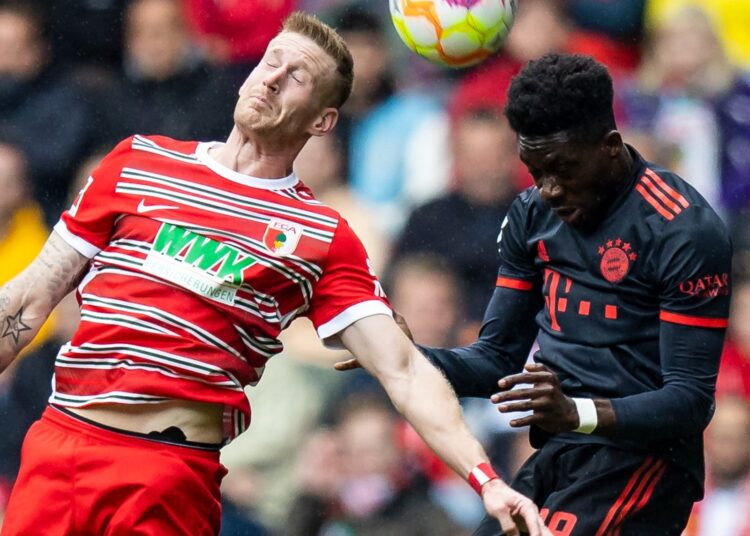 Augsburg's Andre Hahn (L) and Munich's Alphonso Davies challenge for the ball during their German Bundesliga match.