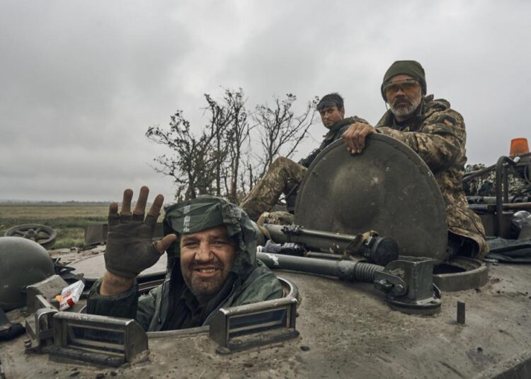 An Ukrainian soldier smiles from a military vehicle on the road in the freed territory in the Kharkiv region, Ukraine, on Monday, September 12, 2022.