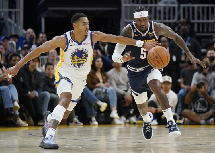 Golden State Warriors Jordan Poole (L) reaches for the ball in front of Denver Nuggets Kentavious Caldwell-Pope during their NBA game on Oct. 14, 2022.
