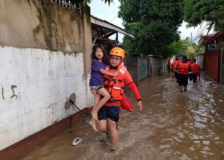 A Philippine Coast Guard (PCG) rescuer evacuates a child following flooding due to Tropical Storm Nalgae, in Zamboanga, Philippines, October 29, 2022. Philippine Coast Guard/Handout via REUTERS. THIS IMAGE HAS BEEN SUPPLIED BY A THIRD PARTY. NO RESALES. NO ARCHIVES