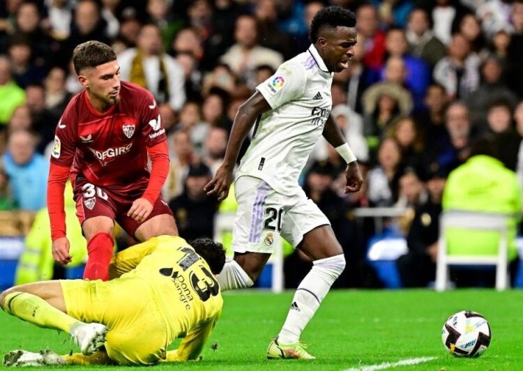 Madrid beats Sevilla, increases La Liga lead 1 - Egyptian Gazette Real Madrid's Brazilian Vinicius Junior (R) fights for the ball with Sevilla's Spanish defender Jose Angel Carmona (L) and Sevilla's Moroccan goalkeeper Yassine Bounou ‘Bono’ (down) during their Spanish La Liga in Madrid.