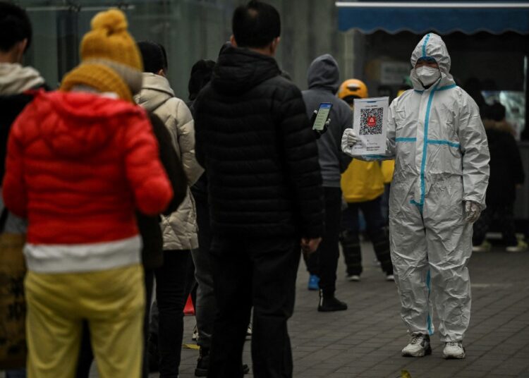 (FILES) This file photo taken on November 20, 2022 shows people queueing to test for the Covid-19 coronavirus at a swab collection station in Beijing. - China's capital Beijing posted a record number of new Covid cases on November 22, 2022, with the city hunkering down under a tightening chokehold of restrictions that have sent schools online, closed many restaurants and forced employees to work from home. (Photo by Noel CELIS / AFP)