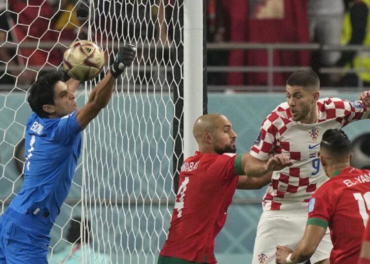 Morocco’s goalkeeper Yassine Bounou (L) makes a save in front of Croatia’s Andrej Kramaric, top right, during the World Cup third-place match on December 17, 2022.