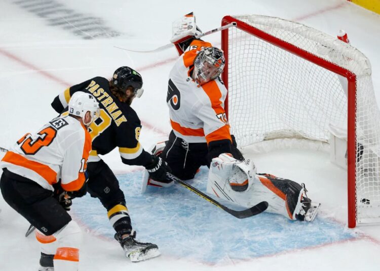 Boston Bruins David Pastrnak (C) scores past Philadelphia Flyers goaltender Carter Hart (R) and Kevin Hayes during an NHL game in Boston.