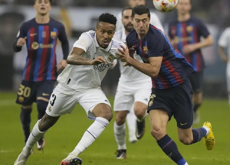 Barcelona wins Spanish Super Cup 1 - Egyptian Gazette Real Madrid's Eder Militao (L) and Barcelona's Robert Lewandowski fight for possession during the final of the Spanish Super Cup in Riyadh, Saudi Arabia.