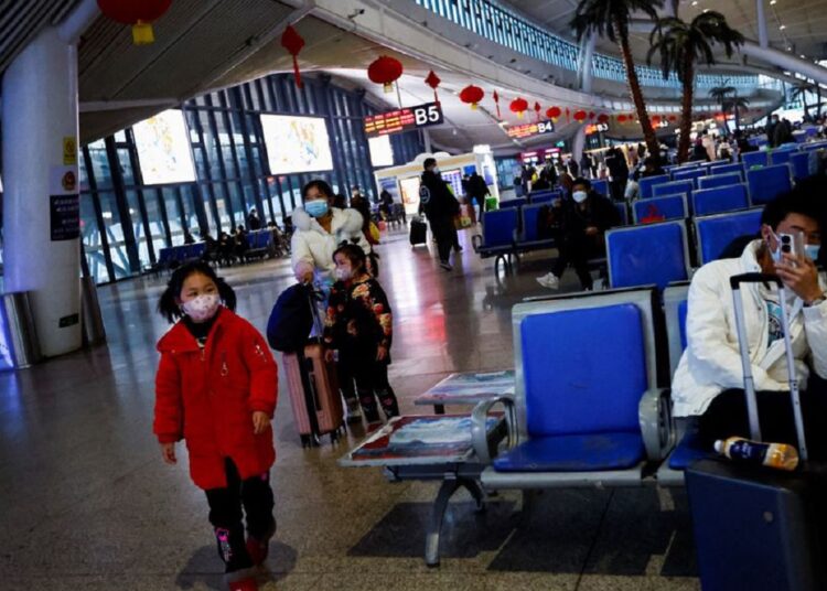 A child walks while people wait with their luggages at a railway station, amid the coronavirus disease (COVID-19) outbreak, in Wuhan, Hubei province, China January 1, 2023.