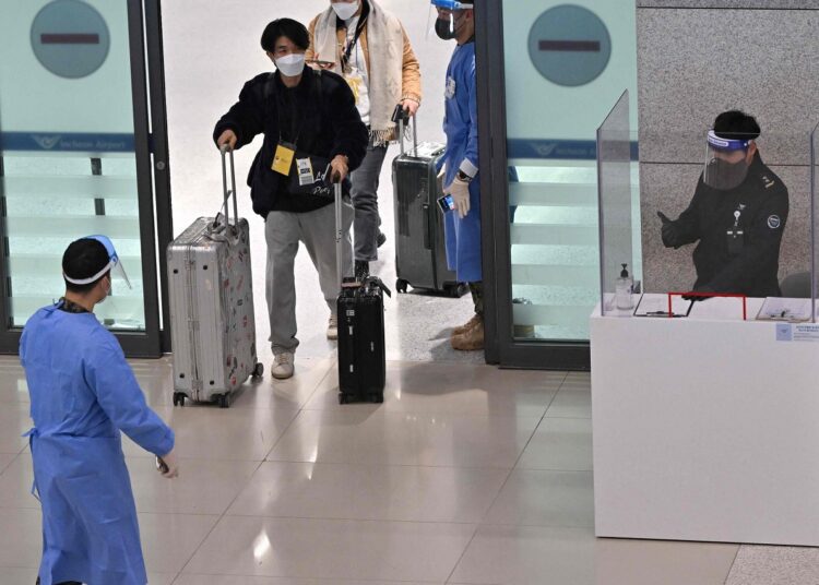 Health workers guided travelers from China arriving in South Korea to a Covid testing center at Incheon International Airport.