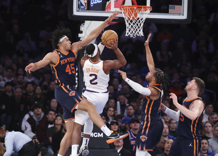Phoenix Suns forward Josh Okogie (2) drives to the basket against New York Knicks center Jericho Sims (45), guard Jalen Brunson, second from right, and center Isaiah Hartenstein, right, during the first half of an NBA game.
