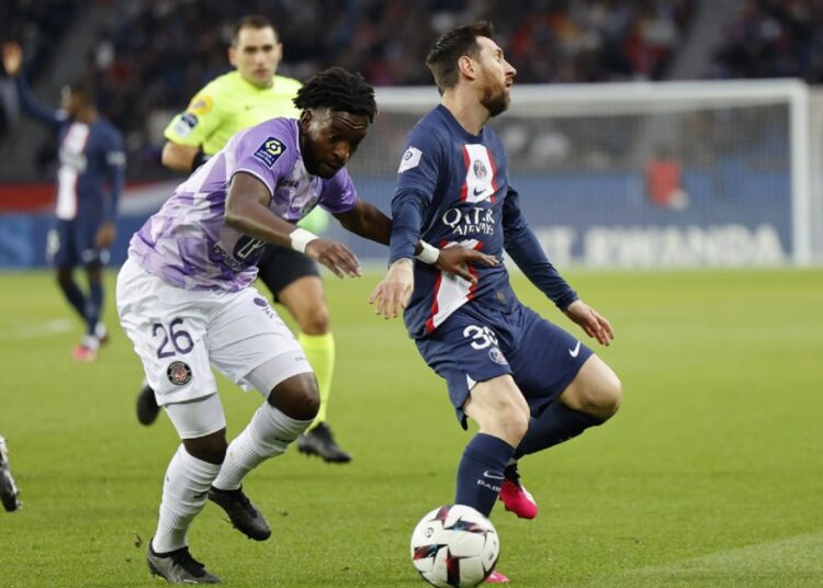 PSG's Lionel Messi (R) challenges for the ball next to Toulouse's Waren Kamanzi during the French League One match, in Paris.