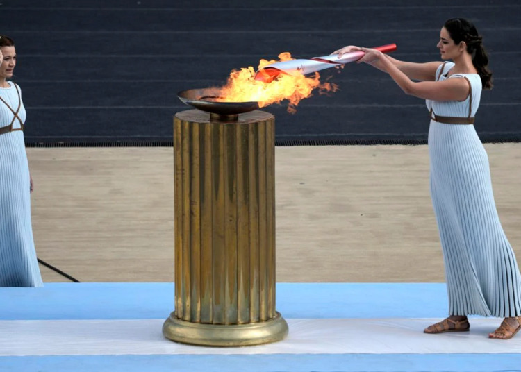 FILE - Greek actress Xanthi Georgiou, playing the role of High Priestess, lights the torch with the flame during the Olympic flame handover ceremony at Panathinean stadium in Athens, Greece, Tuesday, Oct. 19, 2021.