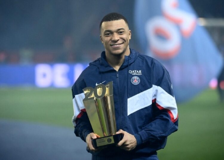 Paris Saint-Germain's French forward Kylian Mbappe poses with a trophy at the end of a ceremony after he became Paris Saint-Germain's all-time top scorer with his 201st goal for the club in their 4-2 win in the French L1 football match against FC Nantes at The Parc des Princes Stadium in Paris.