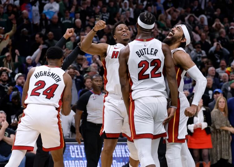 Miami Heat's Jimmy Butler (22), Kyle Lowry (7) and Gabe Vincent react at the end of overtime against the Milwaukee Bucks in Game 5 in a first-round NBA basketball playoff series in Milwaukee.