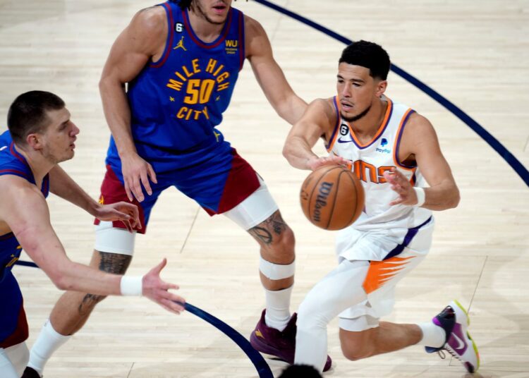 Phoenix Suns Devin Booker (R) passes the ball as Denver Nuggets Nikola Jokic (L) and Aaron Gordon (50) defend in the first-half of Game 1 of an NBA second-round basketball series in Denver.