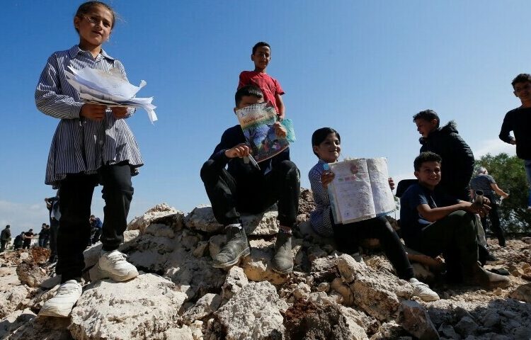 Palestinian students showing damaged books after Israeli machinery demolish a school near Bethlehem in the Israeli-occupied West Bank, May 7.