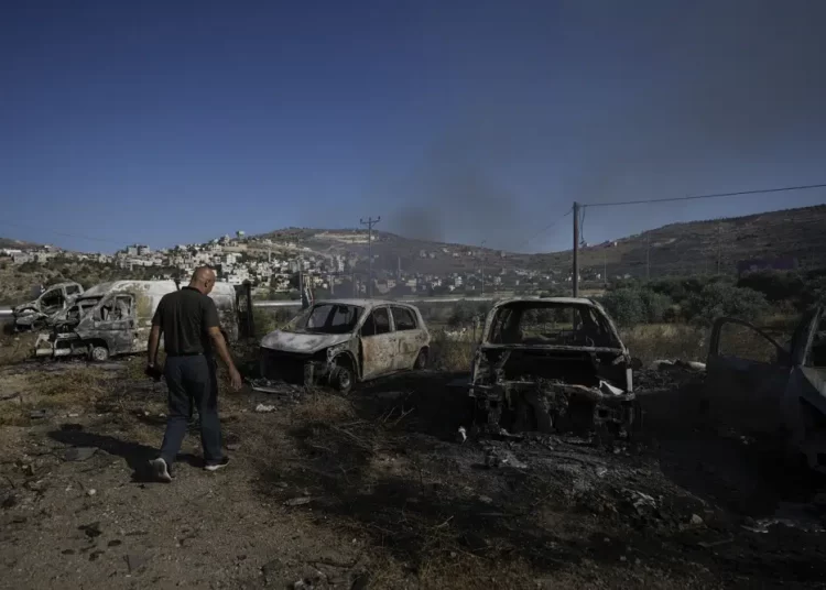 Israel beefs up troop presence in West Bank after Palestinian attack that killed 4 civilians 1 - Egyptian Gazette A Palestinian man inspects scorched cars, including some junked for spare parts, in the West Bank village of A Laban al-Sharkiyeh, Wednesday, June 21, 2023. Israeli settlers set fire to cars after four Israelis were killed by Palestinian gunmen in the northern West Bank on Tuesday.