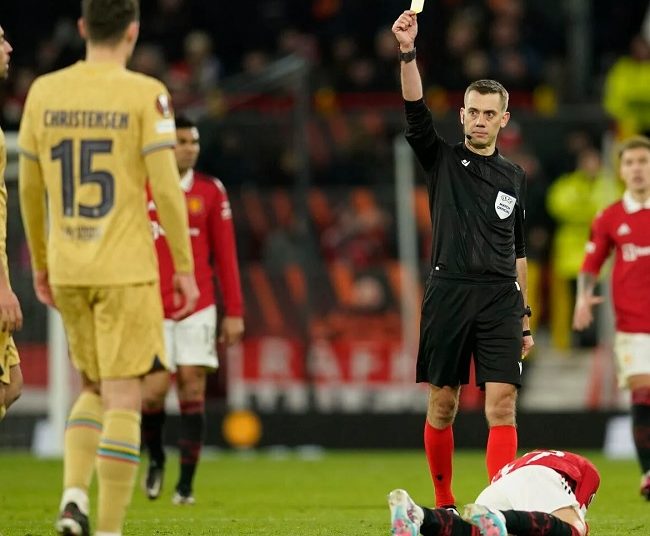 Barcelona, Man United fined by UEFA 1 - Egyptian Gazette Referee Clement Turpin shows a yellow card to Barcelona's Sergio Busquets, left, after he fouled Manchester United's Alejandro Garnacho, ground, during the Europa League playoff match on Feb. 23, 2023.