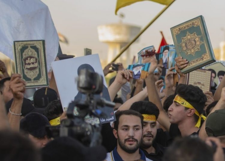 Muslim-majority nations express outrage over Quran desecration in Sweden 1 - Egyptian Gazette Iraqis raise copies of the Quran, Muslims' holy book, during a protest in Tahrir Square in Baghdad, Iraq.