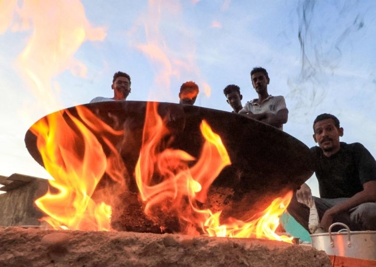 A file photo of people sitting around food cooking on a bonfire at a school that has been transformed into a shelter for people displaced by conflict in Sudan’s northern border town of Wadi Halfa near Egypt on September 11, 2023.