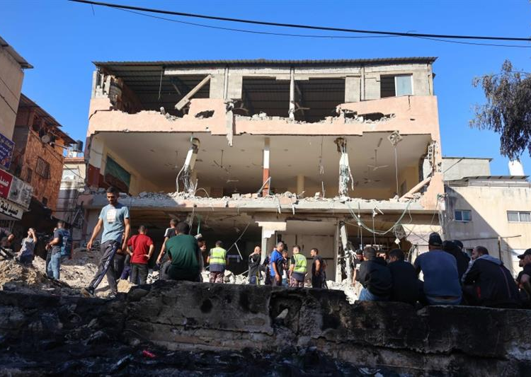 People gather in front of a damaged building following a raid by Israeli troops on the Palestinian Nour Shams camp in Tulkarm, in the occupied West Bank on October 20, 2023.