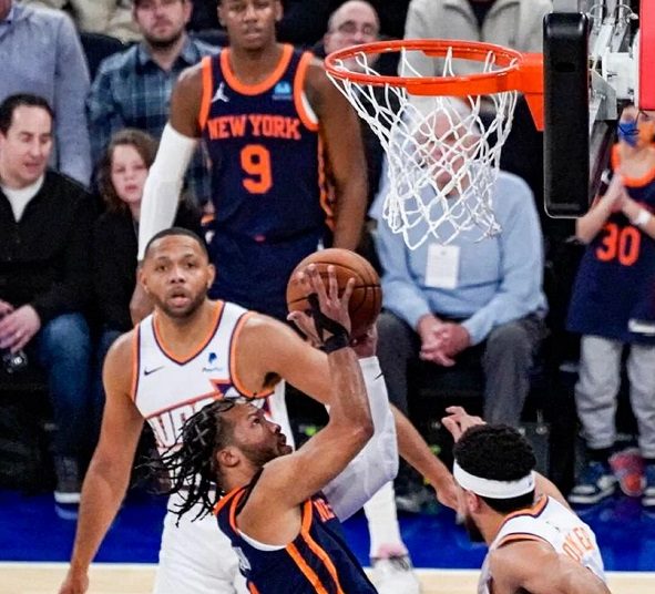 New York Knicks Jalen Brunson (C) takes a contested shot over Phoenix Suns Devin Booker (R) during an NBA basketball game in New York.