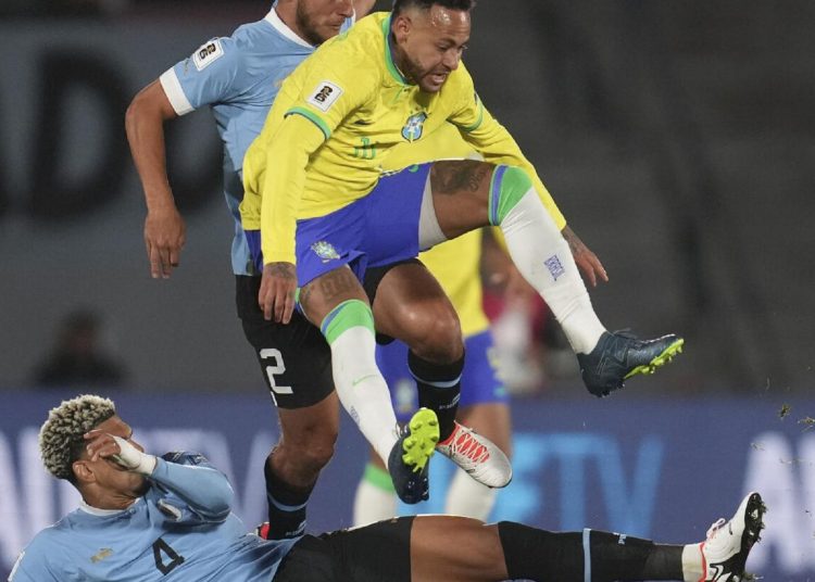 Brazil's Neymar falls while fighting for a ball with Uruguay's Sebastian Caceres during a qualifying soccer match for the FIFA World Cup 2026 in Montevideo, Uruguay on October 17, 2023.