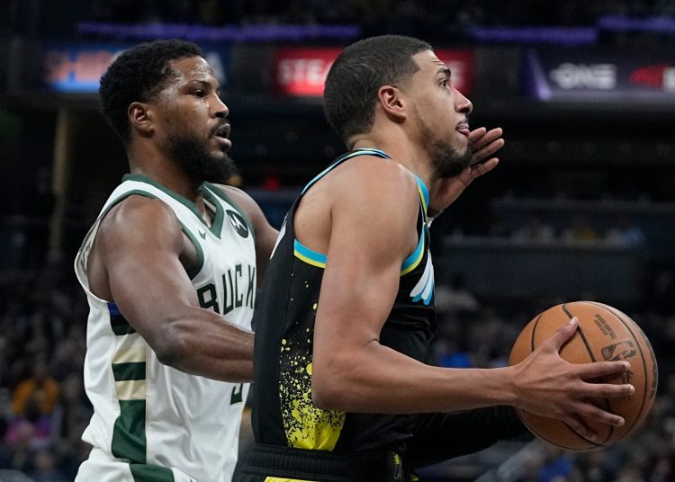 Indiana Pacers' Tyrese Haliburton (R) goes to the basket against Milwaukee Bucks' Malik Beasley during an NBA basketball game.