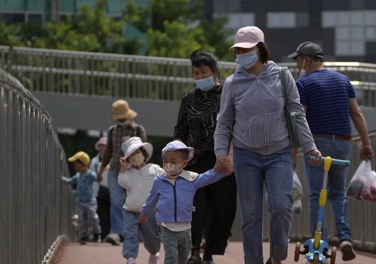 WHO asks China for detail on respiratory illness outbreaks 1 - Egyptian Gazette A file photo shows women wearing face masks walk with masked children along a pedestrian overhead bridge in Beijing.