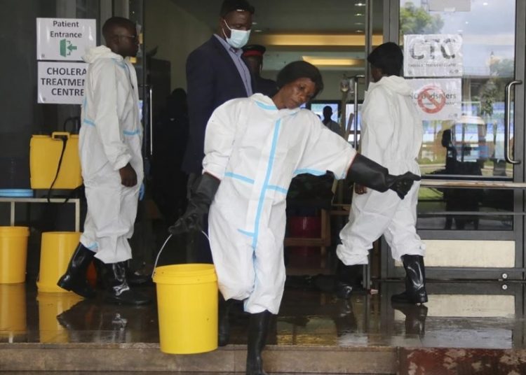 A worker carries a bucketfull of disinfectant at a cholera treatment centre, in Lusaka, Zambia.