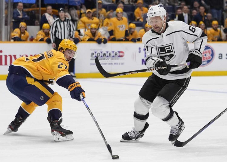 Nashville Predators Ryan McDonagh (L) hits the puck away from Los Angeles Kings Trevor Lewis during their NHL hockey game in Nashville.